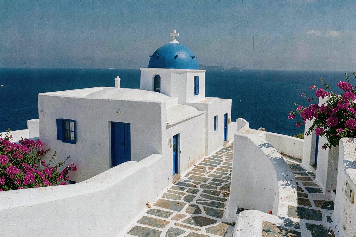 Whitewashed houses and a blue-domed chapel above the Aegean Sea in Greece (illustrative image)