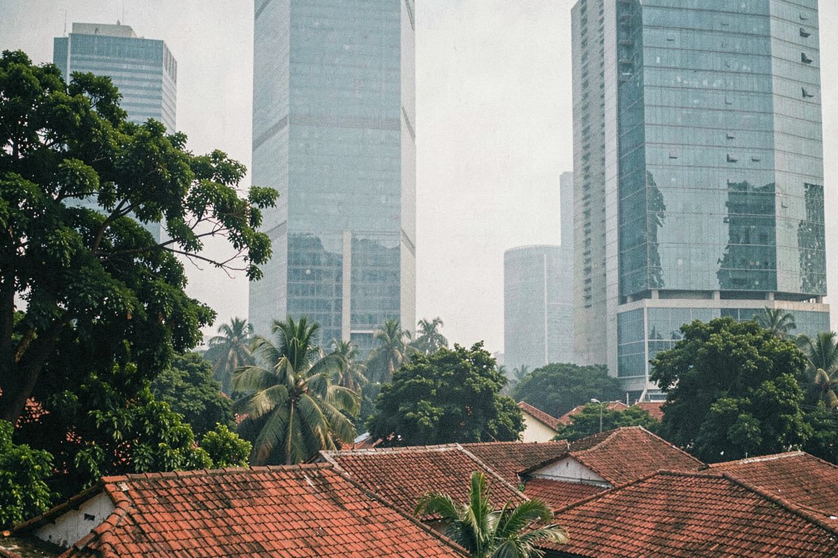 Red-tiled kampung roofs with skyscrapers behind in Jakarta (illustrative image)