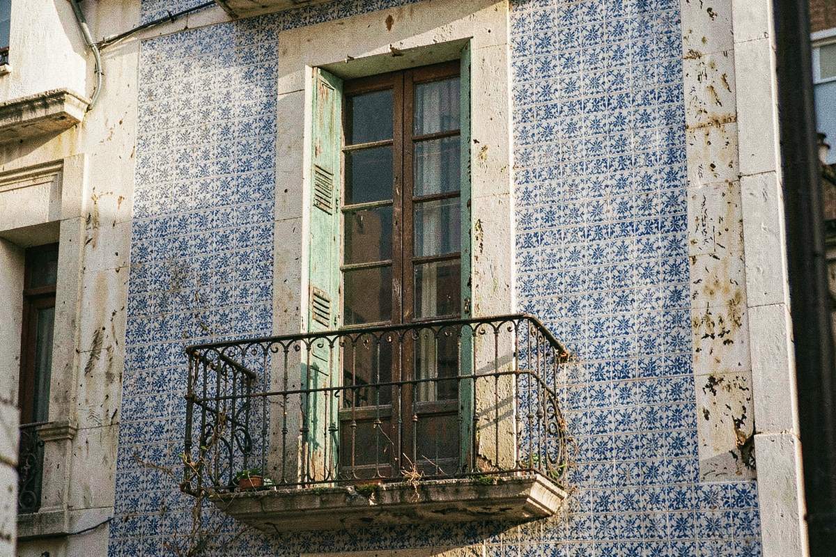 Blue-and-white azulejo tiled facade with an iron balcony in Portugal (illustrative image)