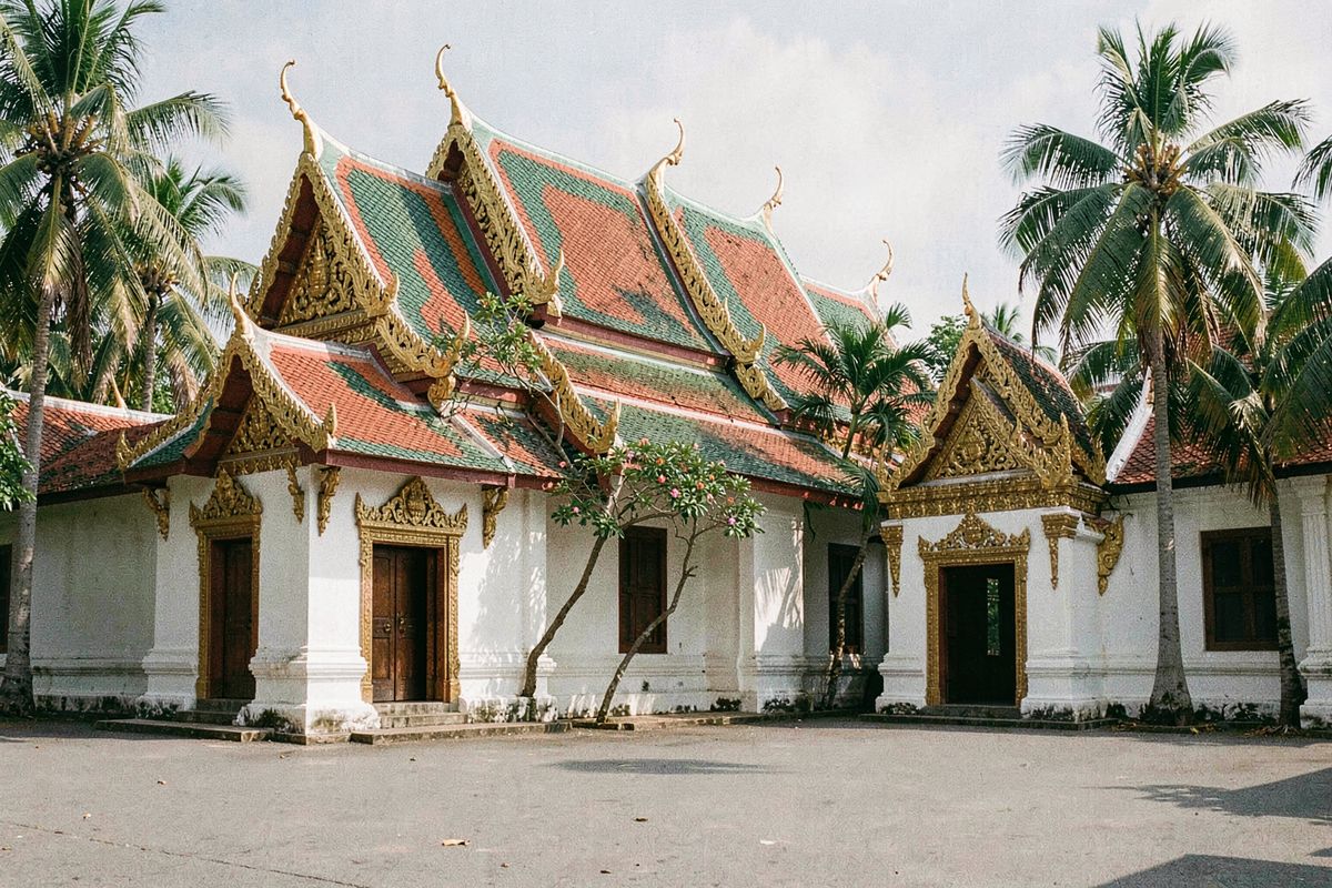 Tiered red and green temple roofs with golden finials in Thailand (illustrative image)
